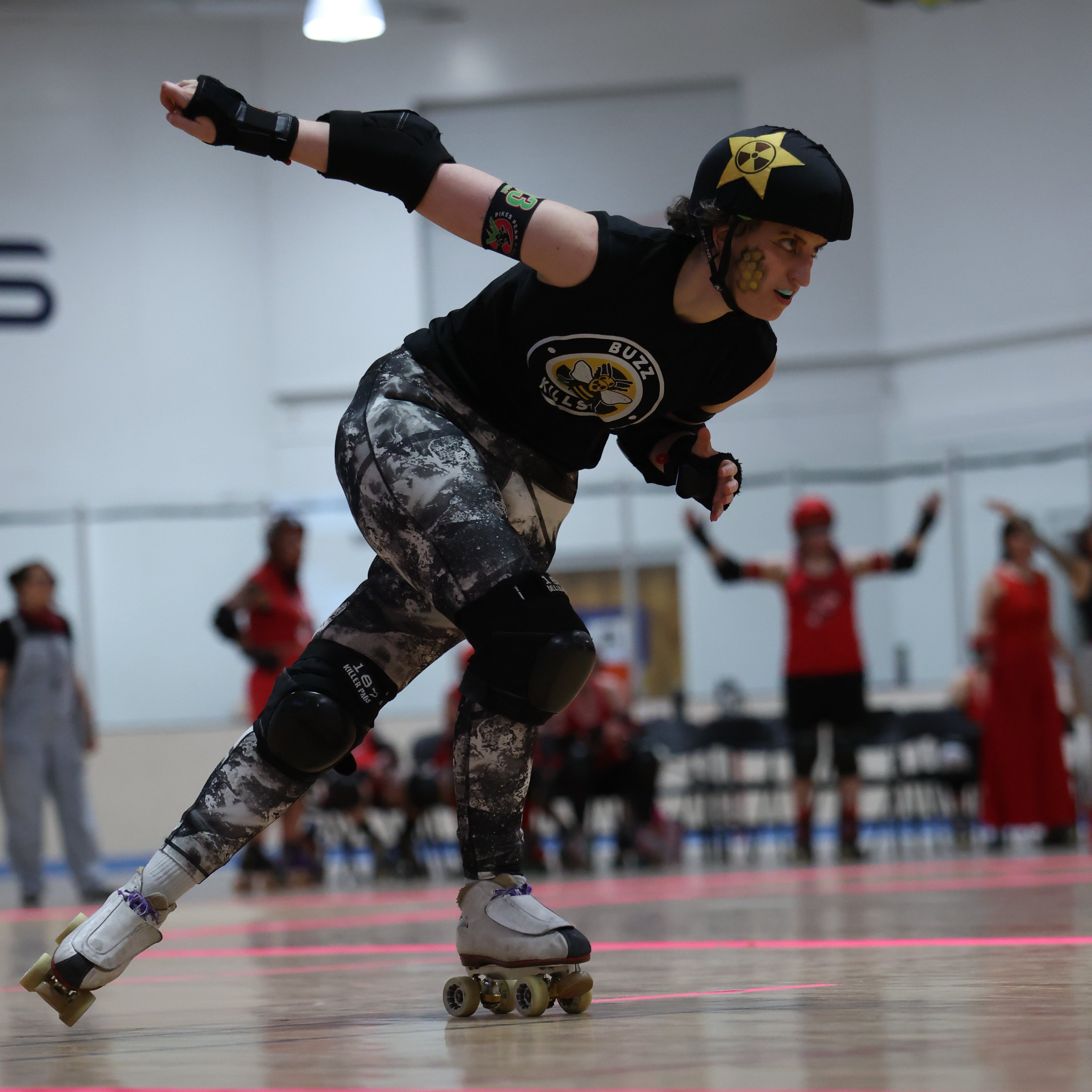 roller derby skater skating at a bout with other skaters in the background